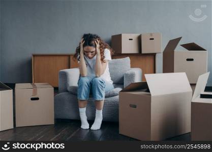 Tired european woman sitting among packed boxes. Girl is upset with moving. Hopeless young lady in jeans and white t-shirt getting in trouble. Depression and bankruptcy concept.. Tired european woman sitting among packed boxes. Hopeless young lady getting in trouble