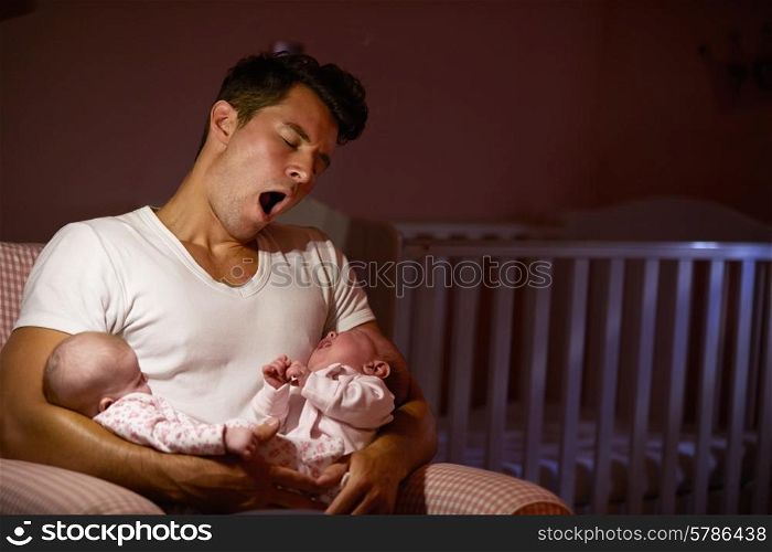 Tired Father At Home Cuddling Twin Baby Daughters In Nursery