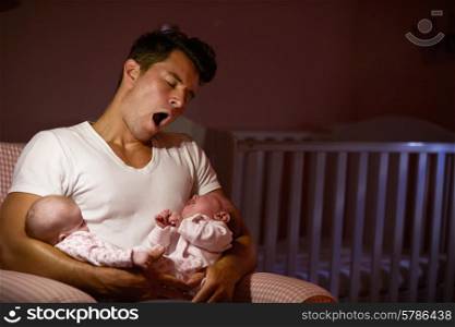 Tired Father At Home Cuddling Twin Baby Daughters In Nursery