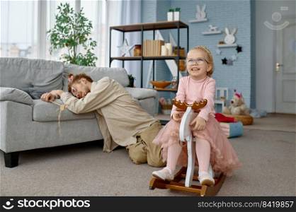 Tired fatigue father sleeping on floor and cute naughty girl playing at home. Tired fatigue father and naughty girl