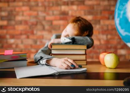Tired female pupil asleep on the stack of textbooks at the table with opened notebook. Schoolgirl sleeping at the desk in the school. Tired female pupil asleep on stack of textbooks