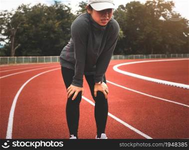 Tired female runner taking a rest after running hard on stadium track. Workout Healthy lifestyle concept.
