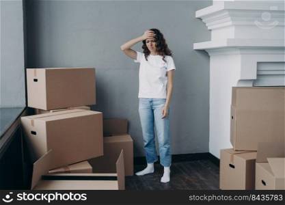 Tired girl is moving. Woman getting headache from boxes packing. Annoyed young lady in jeans and white t-shirt is going to relocate. Homeowner gathering things and getting away from luxurious house.. Tired girl is moving. Woman getting headache from boxes packing and going to relocate.
