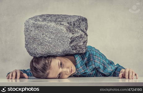 Tired girl under pressure. Women crushed by the weight of stone o table