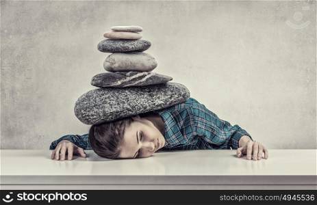 Tired girl under pressure. Women crushed by the weight of stone o table