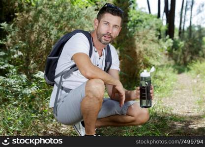 tired hiker having a break drinking a bottle of water