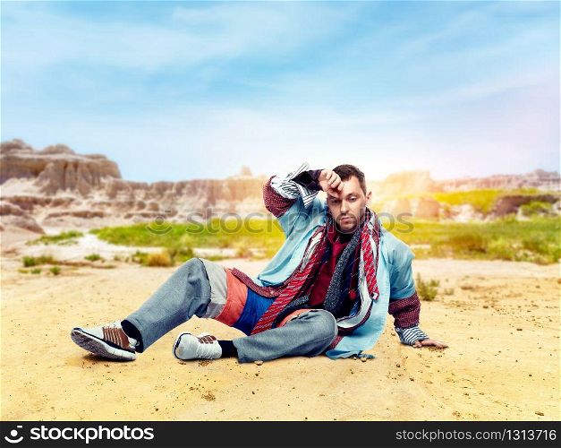 Tired male consumer after clothing store, desert valley on background. Shopping concept