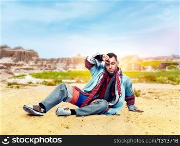Tired male consumer after clothing store, desert valley on background. Shopping concept