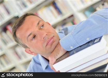 tired man resting on a pile of books