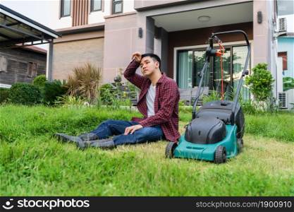 tired man sitting with a lawn mower for cutting grass at home