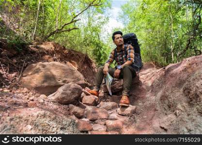 tired man traveler with backpack sitting and resting in the natural forest