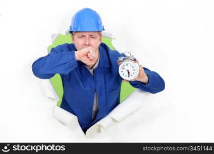 Tired manual worker holding alarm clock