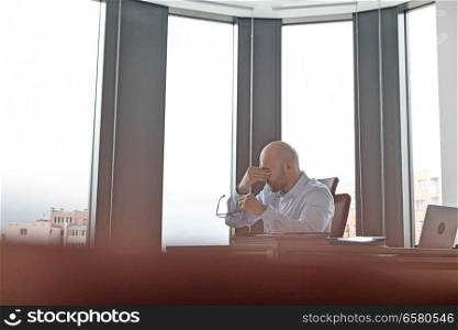 Tired mid adult businessman rubbing eyes in office