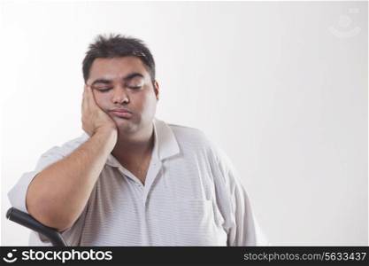 Tired obese man with hand on chin over white background