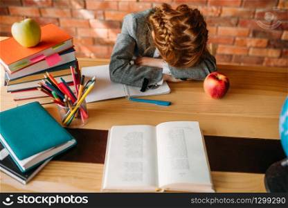 Tired schoolgirl asleep at the table with opened notebook. Female pupil sleeping at the desk in the school