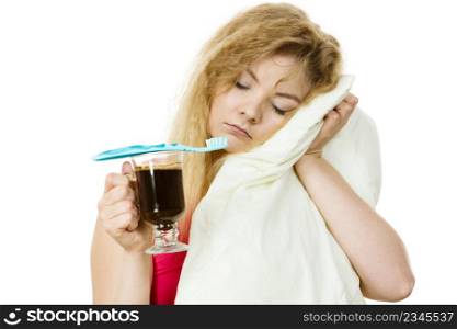 Tired sleepy and grumpy woman holding toothbrush and coffee going to brush her teeth after hot drink.. Tired woman holding toothbrush and coffee