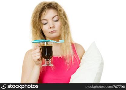 Tired sleepy and grumpy woman holding toothbrush and coffee going to brush her teeth after hot drink.. Tired woman holding toothbrush and coffee