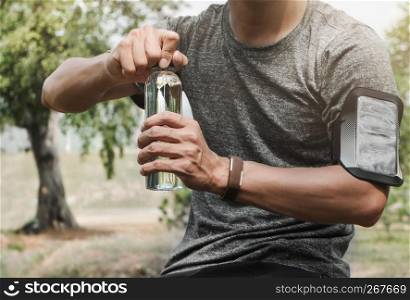 Tired Sports man opening a bottle of water with nature background.