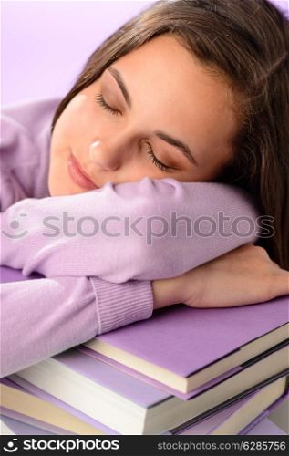Tired student girl sleeping on stack of books purple background