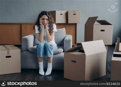 Tired unhappy young woman tenant sits in armchair with carton boxes feels unmotivated for packing things, moving out rented dwelling. Upset hispanic female stressed by relocating. Hard relocation day.. Tired sad girl sits with cartons feels unmotivated to pack things for moving. Hard relocation day