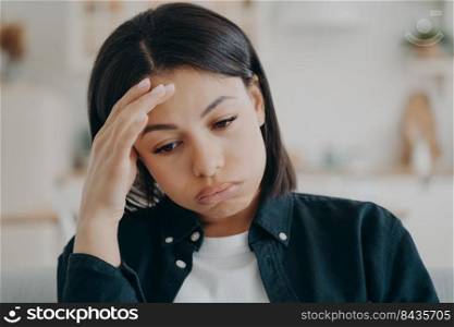 Tired unwell arab woman has headache. Young lady touches forehead with fingers and suffering problem. Overworked stressed spanish girl portrait indoor. Depression, tension and disease concept.. Tired unwell woman has headache. Young lady touches forehead with fingers and suffering problem.