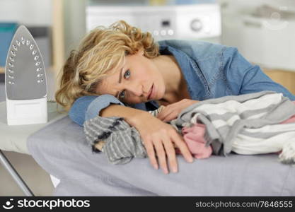 tired woman leaning on her ironing board