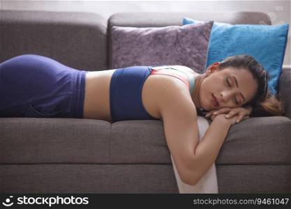 Tired woman lying down on sofa after exercise