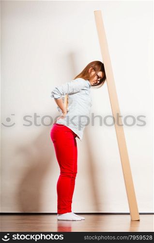 Tired woman moving into apartment carrying box.. Unhappy tired woman moving into new apartment house carrying heavy carton box with furniture. Young girl arranging interior and unpacking. Female having backache pain.