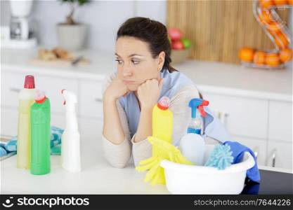 tired woman with cleaning and cleaning products