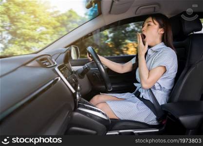 tired woman yawning and sleepy while driving a car