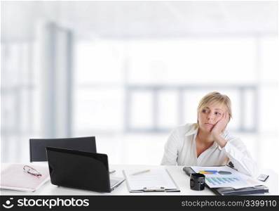 tired young blonde woman in the office at the workplace suffers headaches.