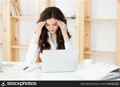 Tired young businesswoman suffering from long time sitting at computer desk in office.. Tired young businesswoman suffering from long time sitting at computer desk in office