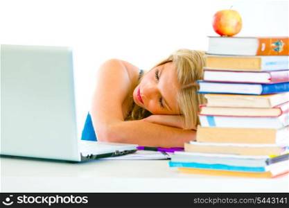 Tired young girl sleeping on table with books and laptop&#xA;