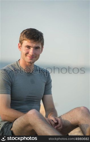 Tired Young Man After Jogging Sitting on Sand at the Beach