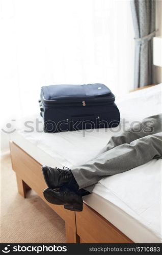 Tired young man lying on bed in hotel room