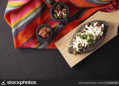 Tlacoyo with Nopales and Cheese. Mexican pre hispanic dish made of blue corn flour patty filled with refried beans. Popular street food in Mexico. Top view.