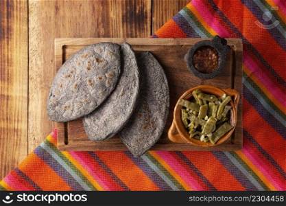 Tlacoyos and Nopales. Mexican pre hispanic dish made of blue corn flour patty filled with refried beans. Popular street food in Mexico. Top view image.