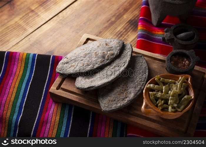Tlacoyos and Nopales. Mexican pre hispanic dish made of blue corn flour patty filled with refried beans. Popular street food in Mexico. Copy space