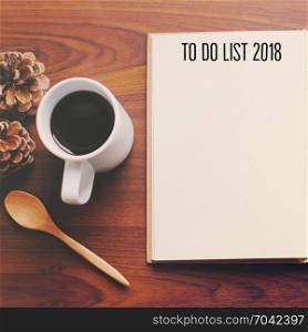 To do list 2018 on blank notebook with coffee and spoon on the wooden table, top view
