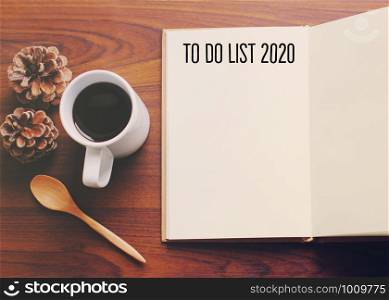 To do list 2020 on flat lay photo of workspace desk with coffee and notebook on table wooden background, new year resolutions concept