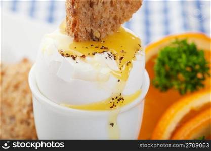 Toast dipped into the warm, runny, yolk of a soft boiled egg.