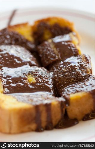 Toast topped with chocolate. Buttered bread topped in chocolate, put on a plate.