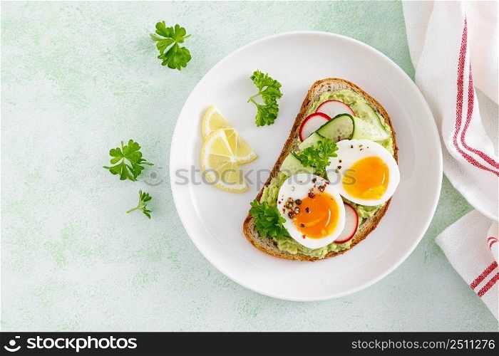 Toast with boiled egg, radish, cucumber and avocado pate. Top view