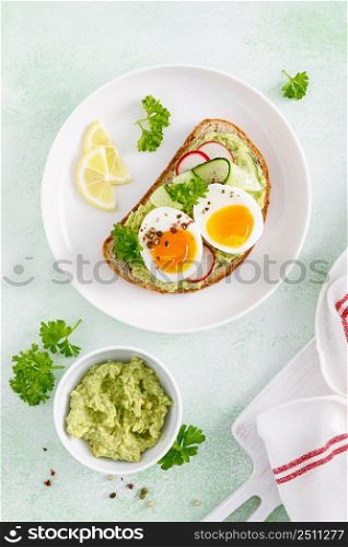Toast with boiled egg, radish, cucumber and avocado pate. Top view