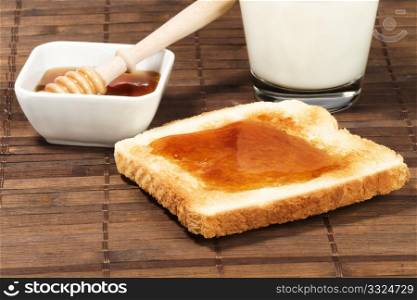 toast with honey and milk. toast with honey, a glass of milk and a honey dipper in a jar with honey