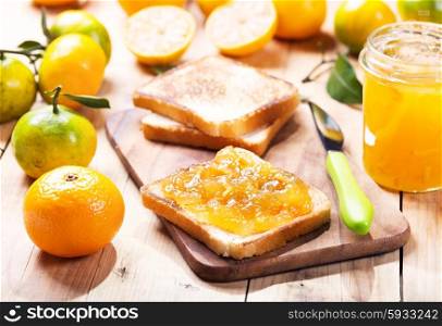 toast with orange mandarin marmalade with fresh fruits on wooden table
