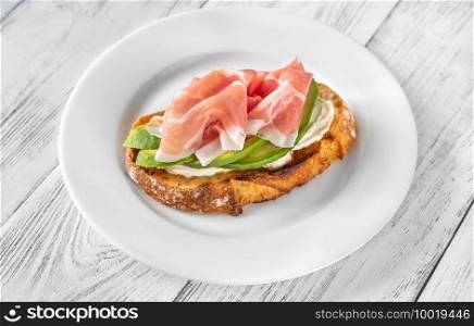 Toast with slices of avocado, prosciutto and cream cheese