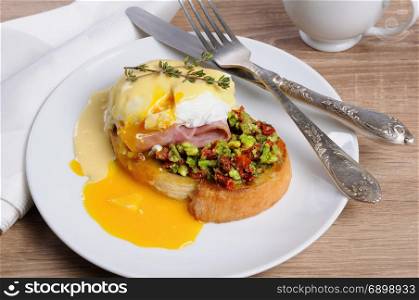Toasted baguette slice with guacamole, ham and eggs Benedict under Dutch sauce