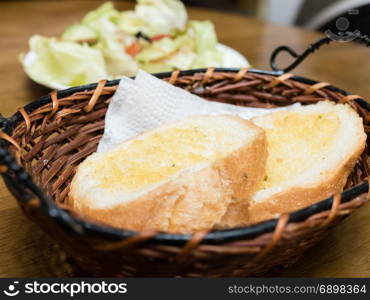 Toasted bread in basket for brunch, with salad in background