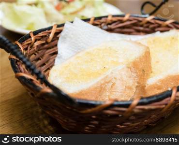 Toasted bread in basket for brunch, with salad in background